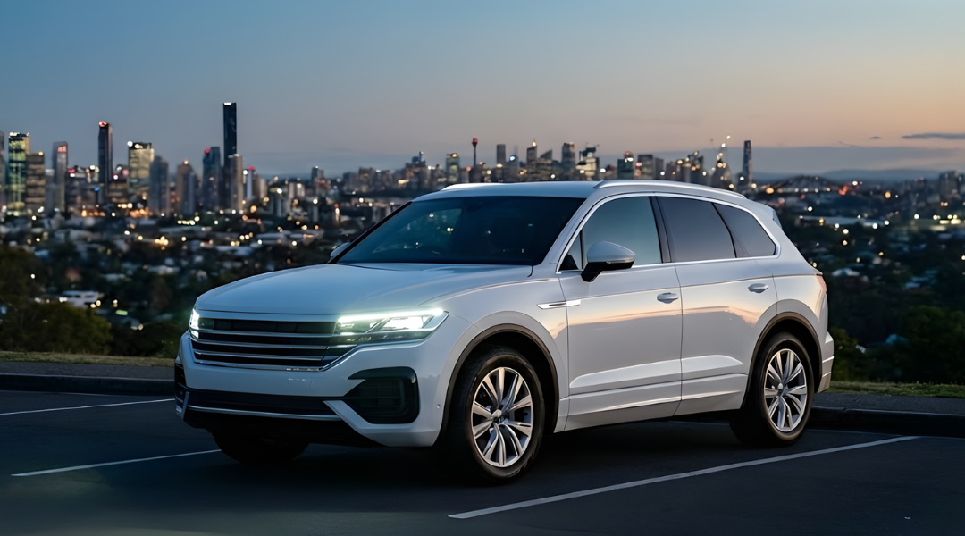 A sleek, white, unbranded SUV parked at a scenic lookout point at twilight/dusk. In the distance, the city lights of an Australian skyline (generic mix of Brisbane/Sydney) are starting to twinkle.