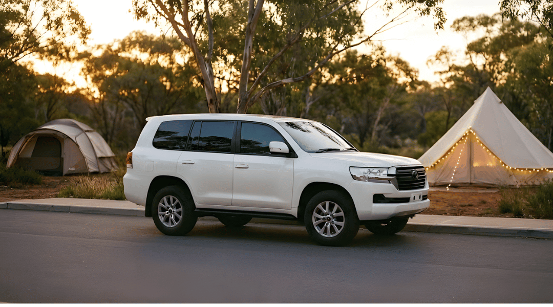 large SUV parked in a scenic Australian bushland setting. In the background, there is a contrast between a traditional dome tent and a luxury "glamping" bell tent with fairy lights